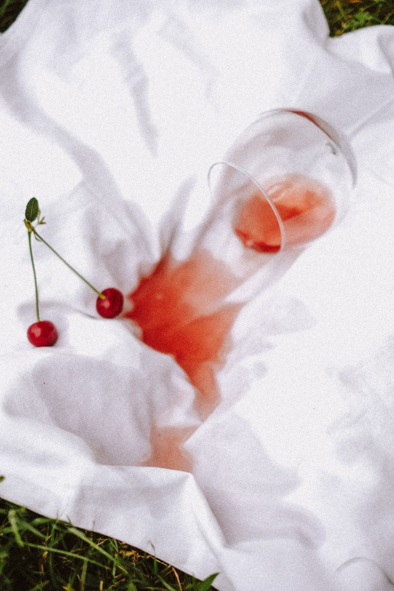 Verre renversé et tache de vin rouge sur une nappe blanche