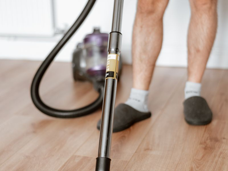 Homme passant l'aspirateur sur un sol carrelé