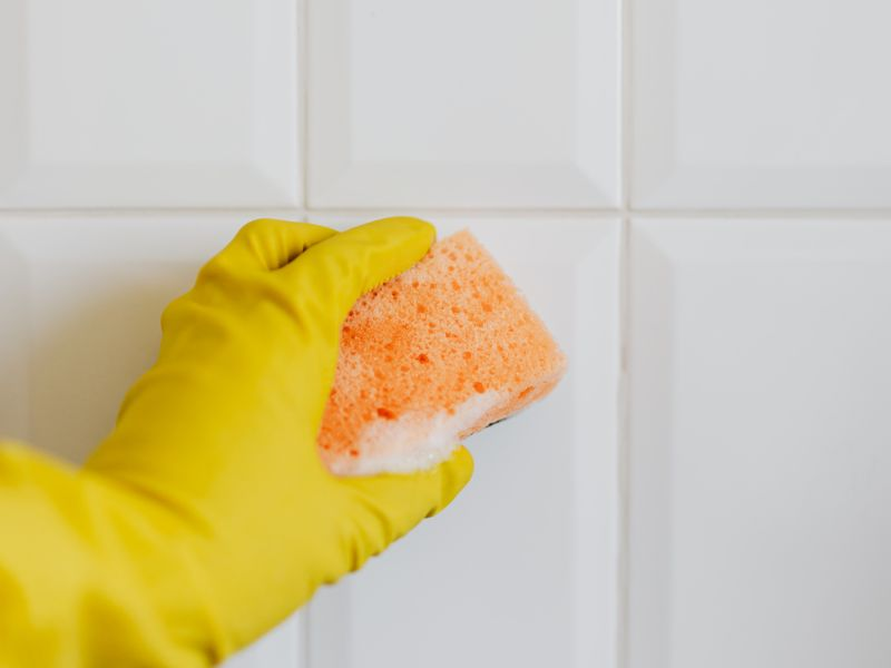 Personne nettoyant du carrelage à l'éponge