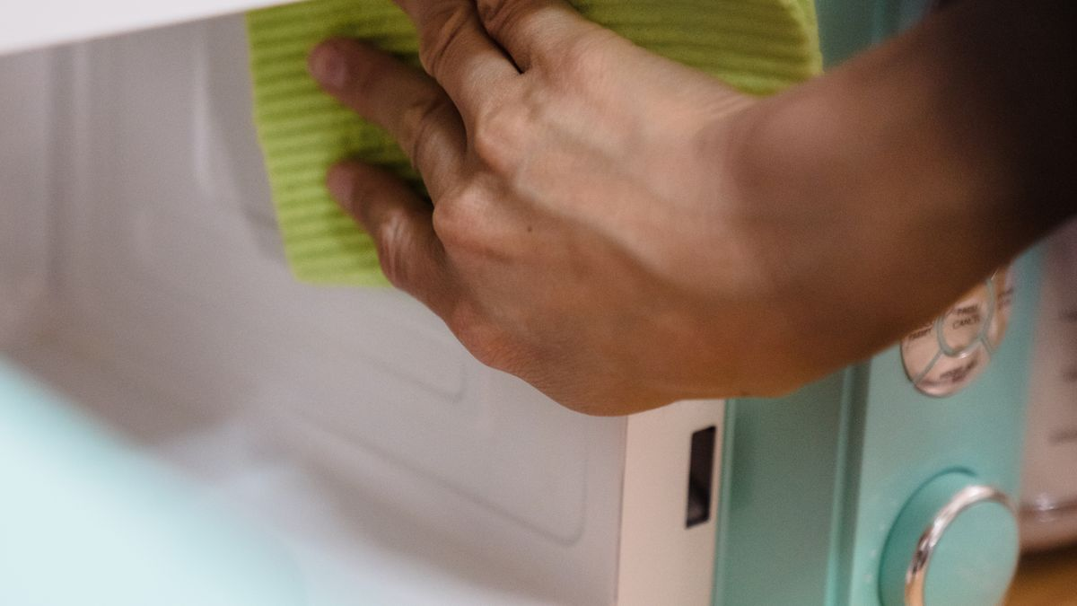 Personne en train de nettoyer l'intérieur d'un four à micro-ondes