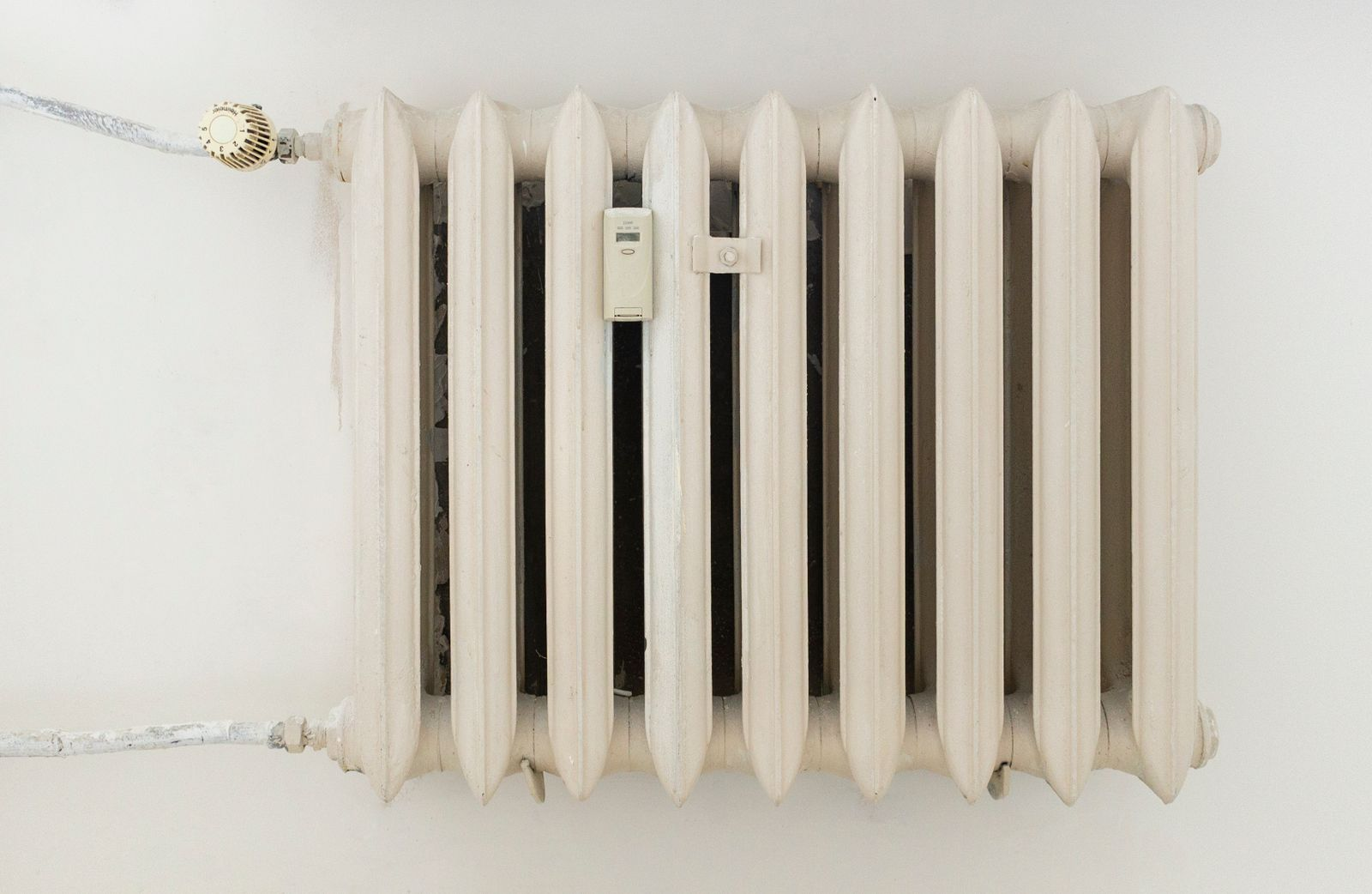 Radiateur blanc à ailettes fixé au mur, avant dépoussiérage